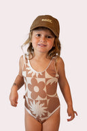 Maillot de bain monokini pour fille en marron avec des fleurs, soleils et vagues, au style surf par la marque de vêtements Natif.
