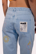Jean tattoos femme, bleu avec des broderies de coeur, soleil et flammes pour un style good vibes assumé