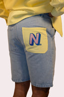 Short Natif en denim, couleur bleu avec poche jaune et logo rose, pour un style good vibes