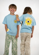 T-shirt Natif del sol, couleur bleu avec un grand soleil, dans un style surf et good vibes pour les enfants.