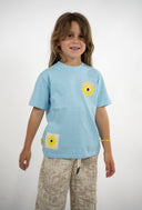 T-shirt Natif del sol, couleur bleu avec un grand soleil, dans un style surf et good vibes pour les enfants.