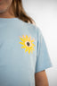 T-shirt Natif del sol, couleur bleu avec un grand soleil, dans un style surf et good vibes pour les enfants.