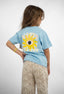 T-shirt Natif del sol, couleur bleu avec un grand soleil, dans un style surf et good vibes pour les enfants.